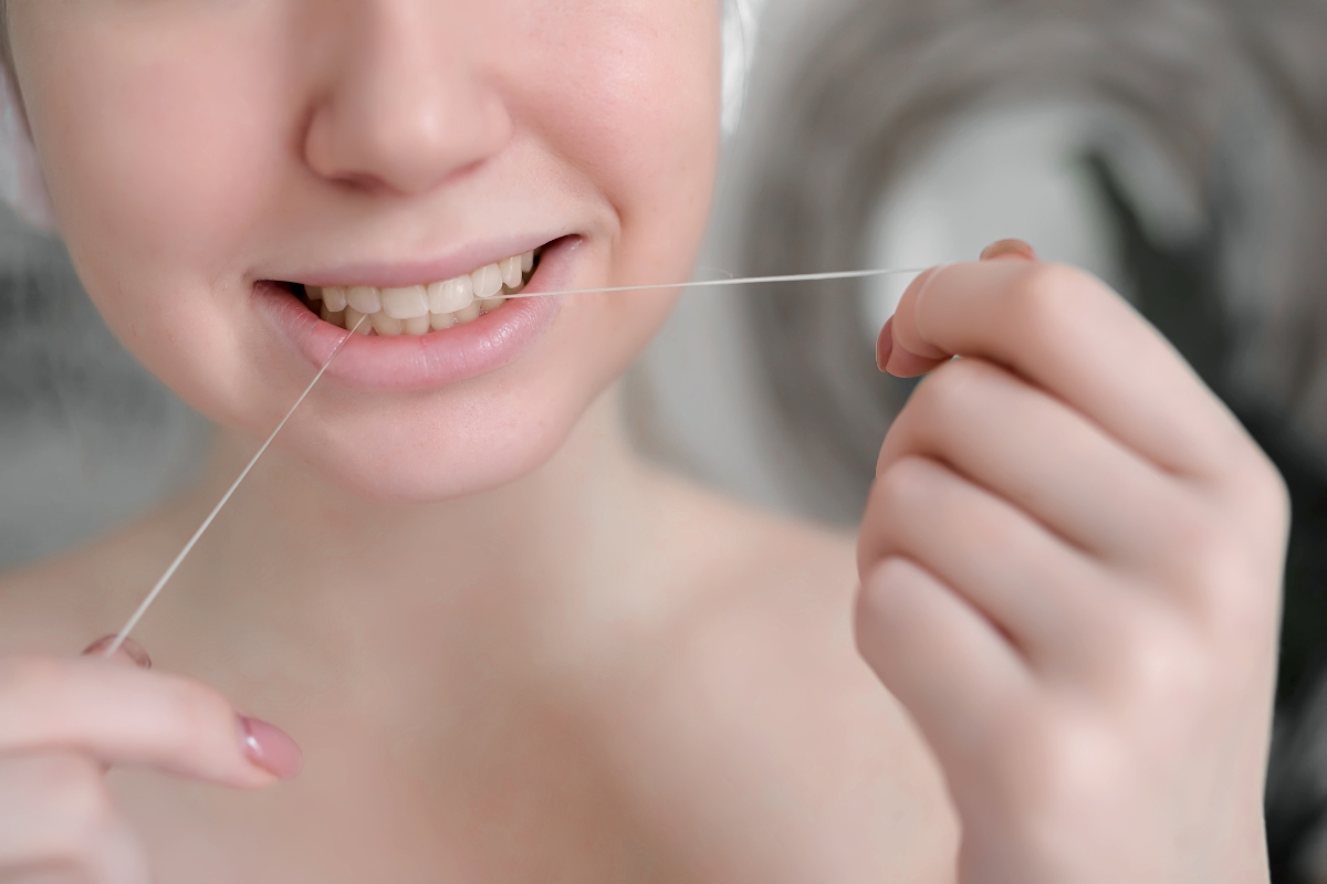 Woman flossing teeth properly to maintain healthy gums and daily oral hygiene routine