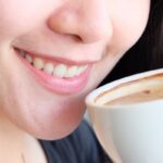 Close-up of woman drinking coffee showing early tooth discoloration and staining from beverages