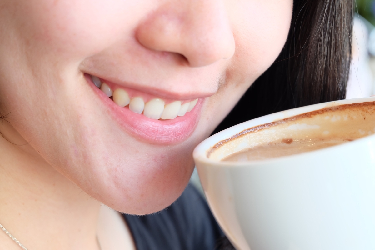 Close-up of woman drinking coffee showing early tooth discoloration and staining from beverages