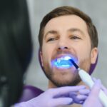 Patient receiving professional teeth whitening treatment with LED light